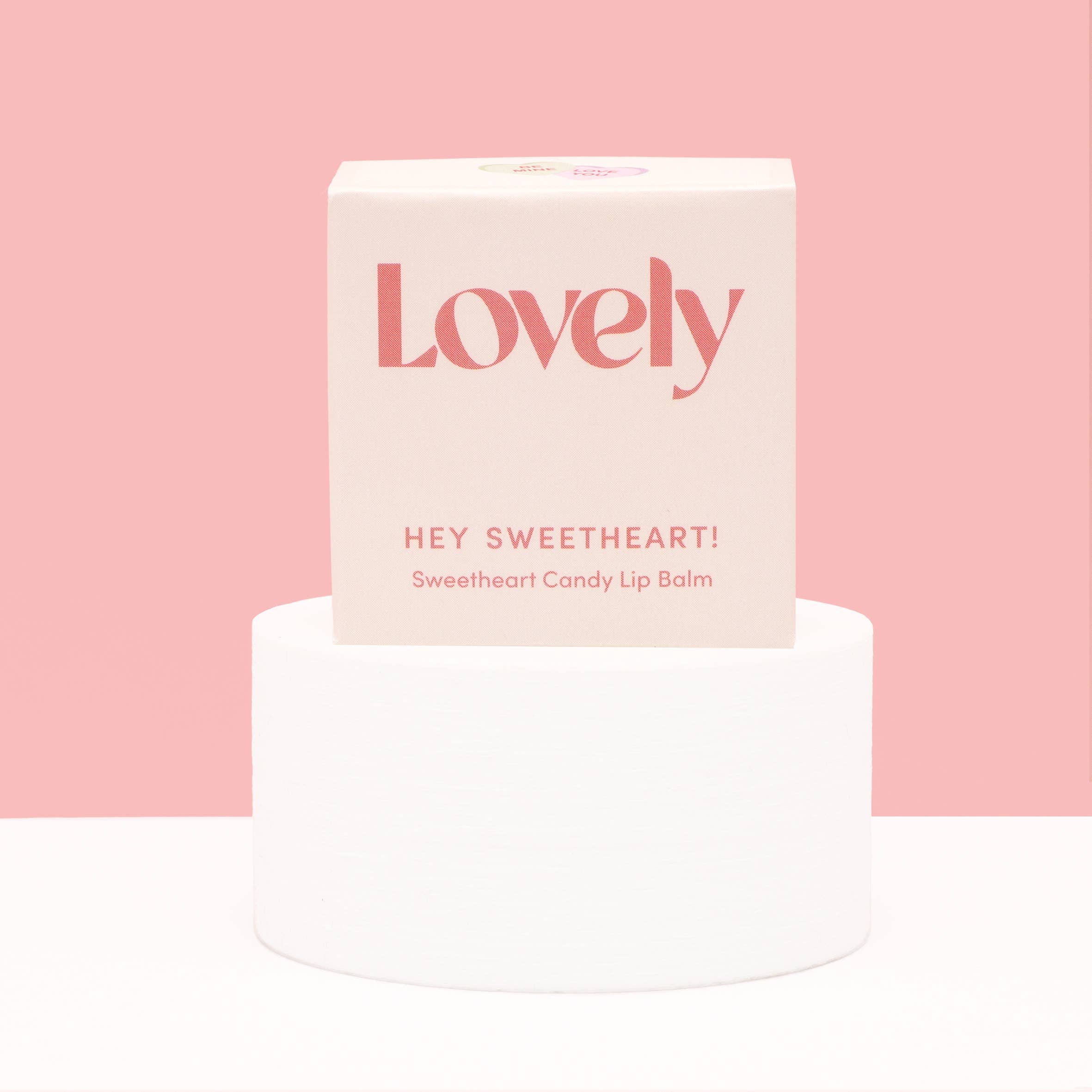 Lip balm packaging with 'Lovely' branding on a pink background