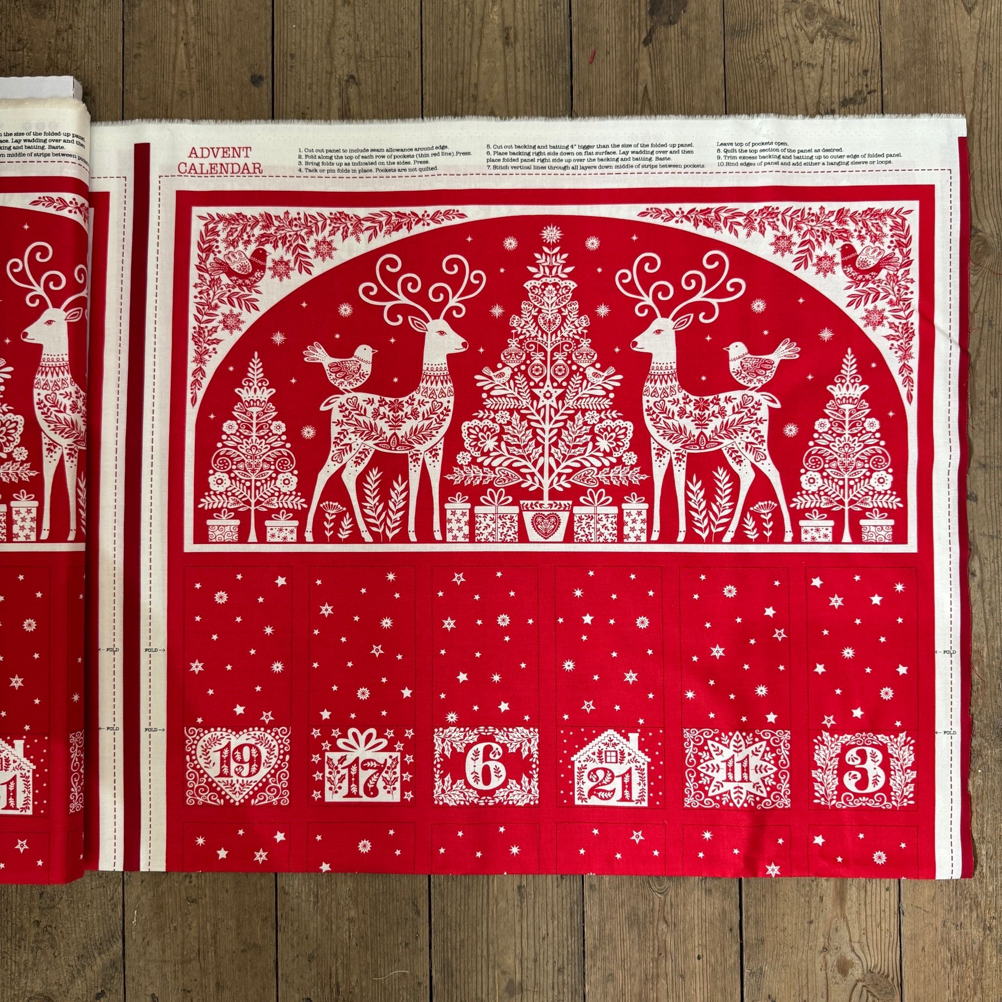 Red and white Advent calendar with reindeer and Christmas tree design on a wooden surface