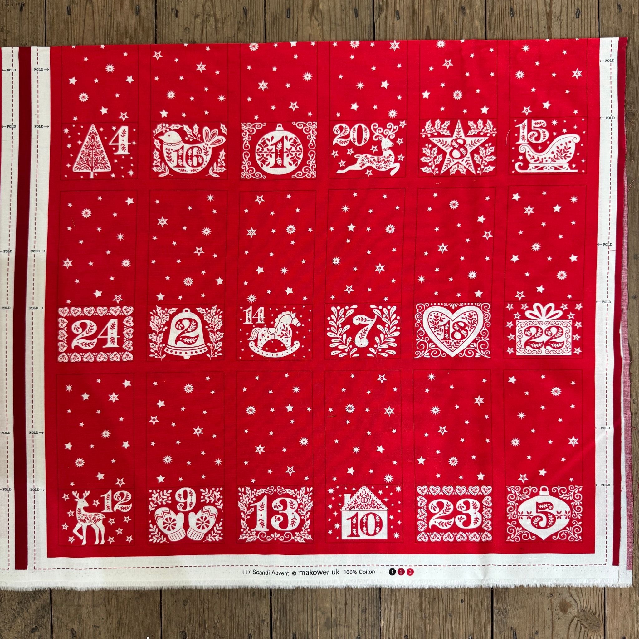 Red fabric with white Christmas-themed numbers and designs on a wooden surface
