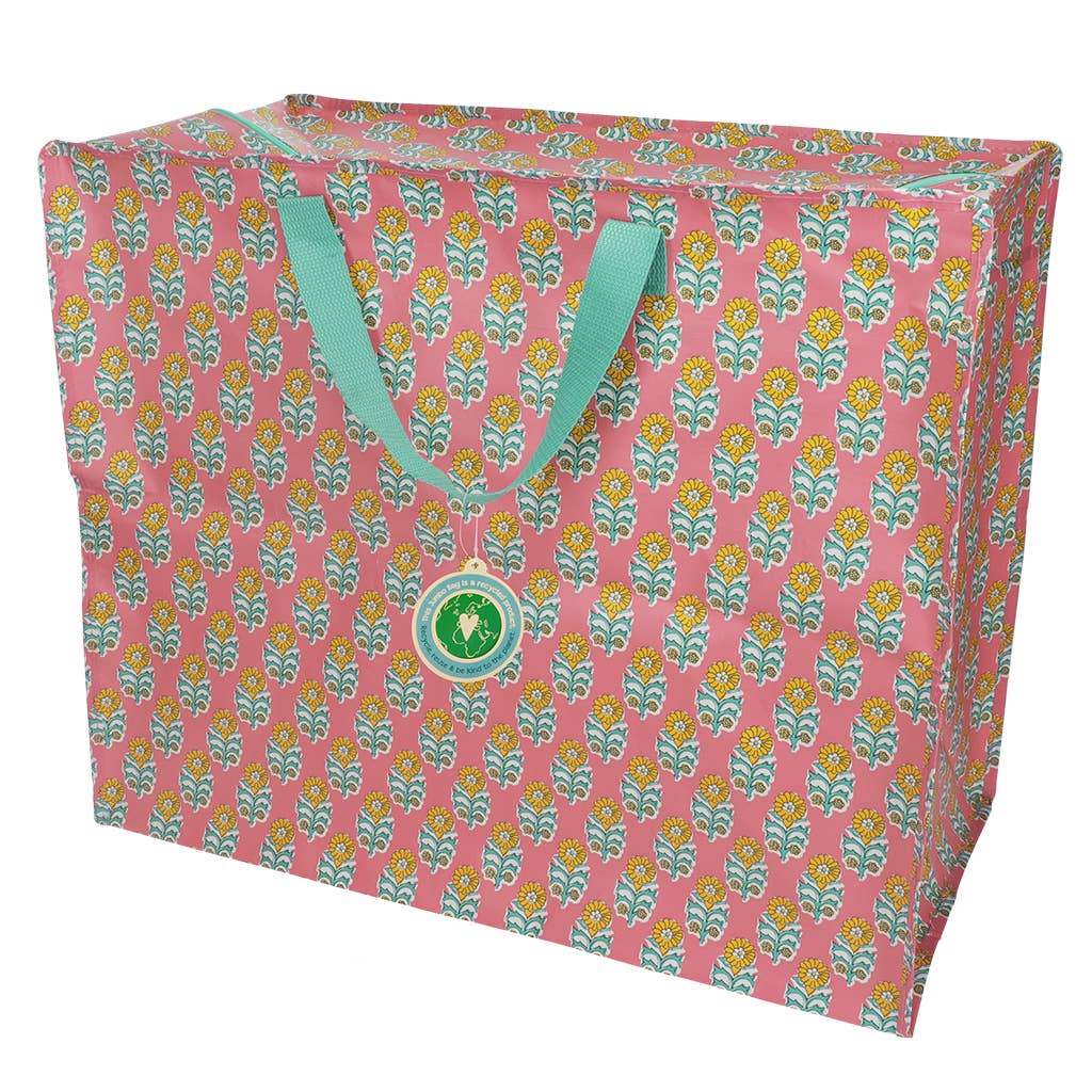 Pink tote bag with floral pattern and green handles on a white background
