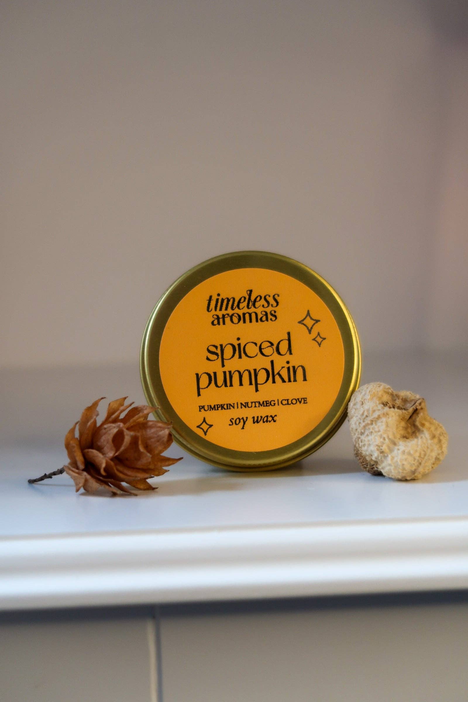Spiced pumpkin candle with decorative elements on a white surface