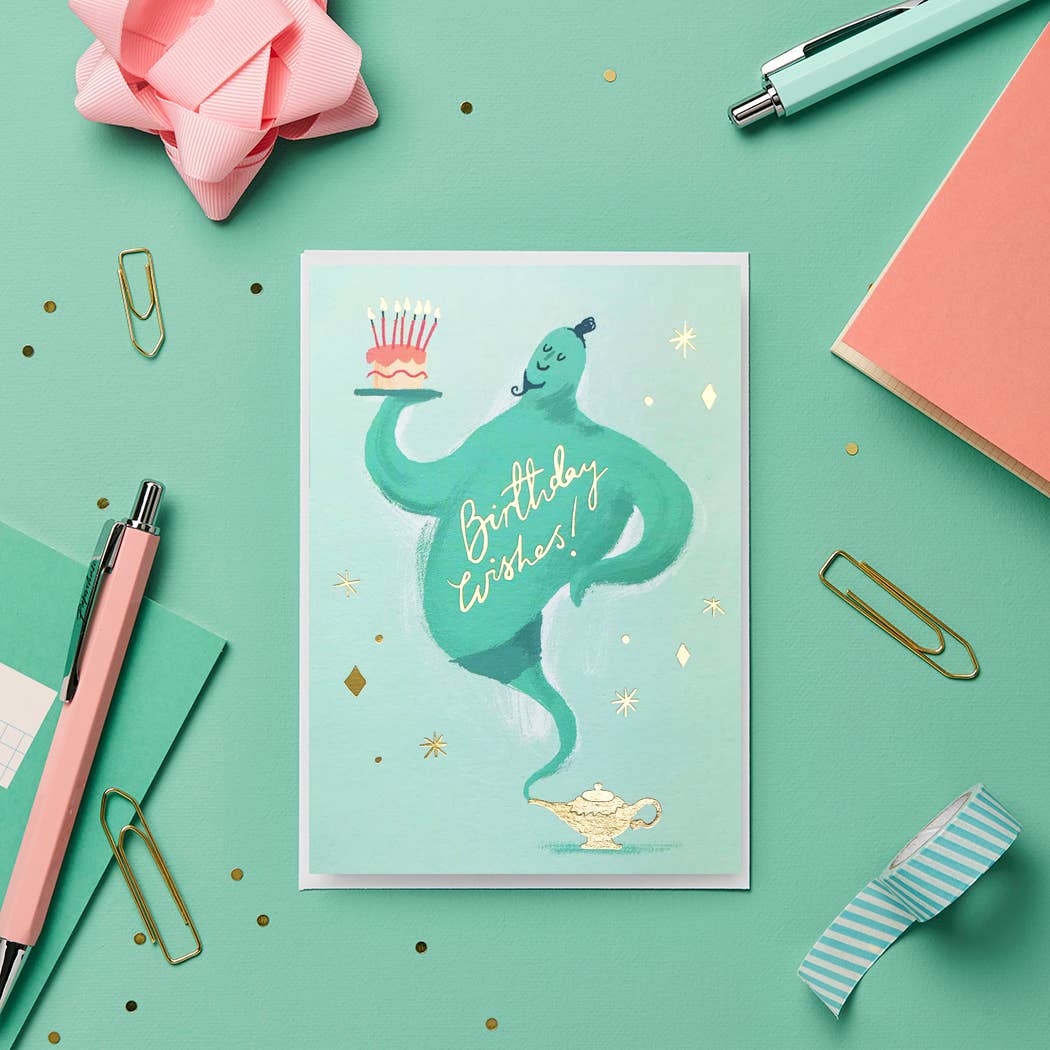 Greeting card with a genie design on a green background with stationery items.