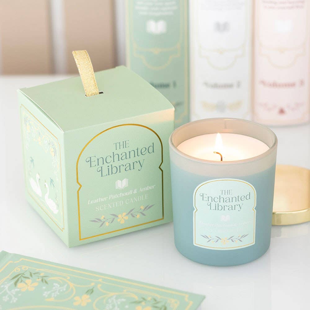 Candle with 'The Enchanted Library' branding in a box on a white surface.