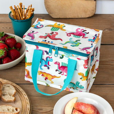 Colorful dinosaur-patterned cooler bag on a wooden table with snacks and fruit.