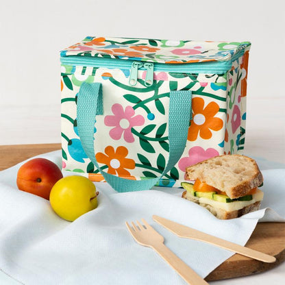 Floral-patterned lunch bag with a sandwich, fruit, and cutlery on a white surface