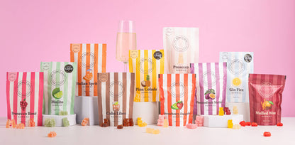 Ask Mummy and Daddy cocktail gummies Assorted fruit snacks in colorful packaging on a pink background