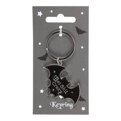 Black bat-shaped keyring on a gray card with decorative elements