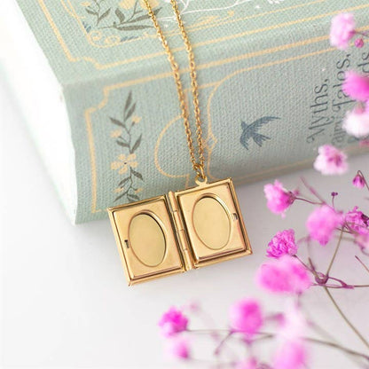 Gold locket necklace on a decorative pillow with pink flowers