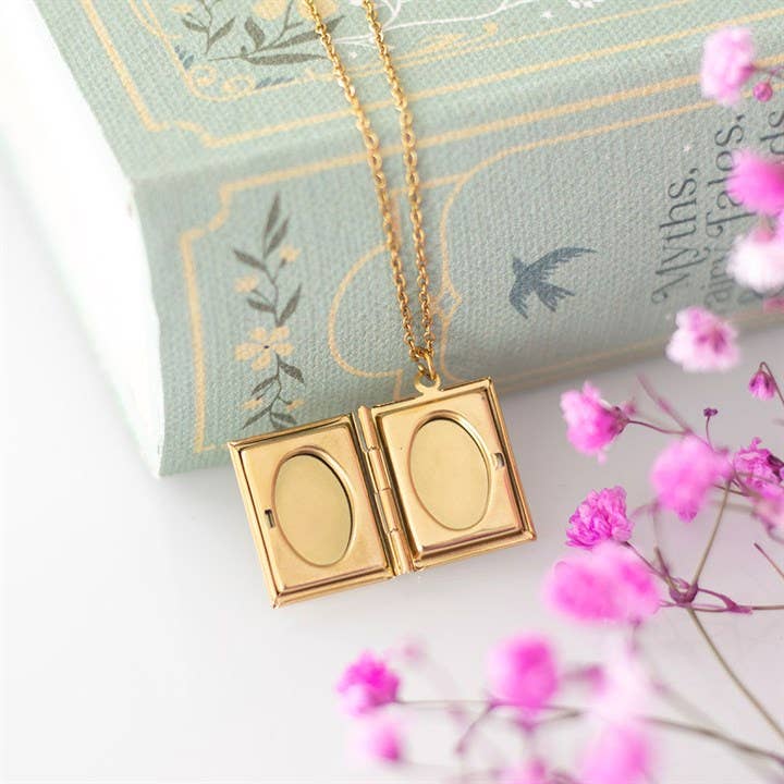 Gold locket necklace on a decorative pillow with pink flowers