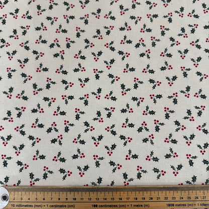 Fabric with holly berry pattern and a ruler for scale on a white background
