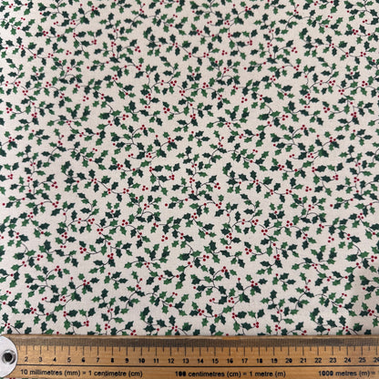 Fabric with holly berry pattern on a white background, ruler at the bottom for scale.
