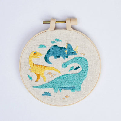 Embroidery hoop with dinosaur designs on a white background