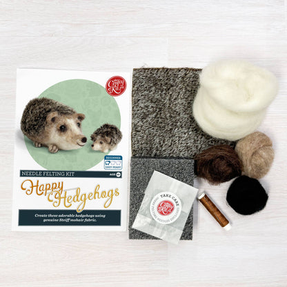 Craft kit for needle felting hedgehogs with felt squares, yarn, and tools on a white background.
