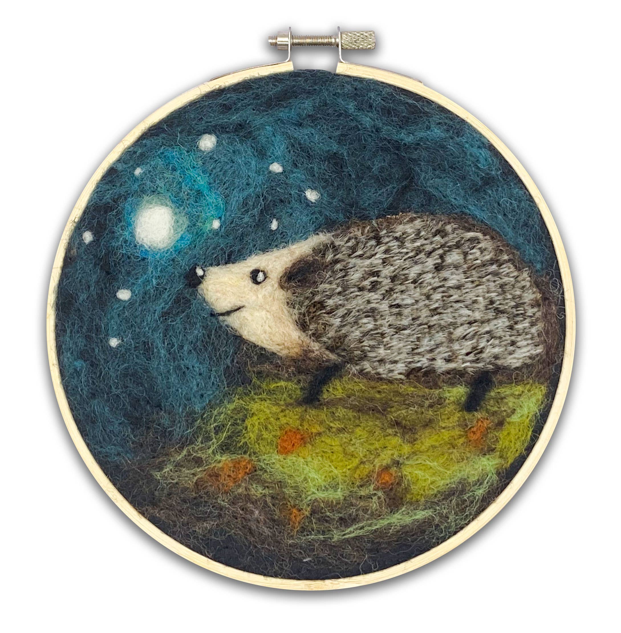 Embroidery hoop with a needle felted hedgehog design against a night sky.