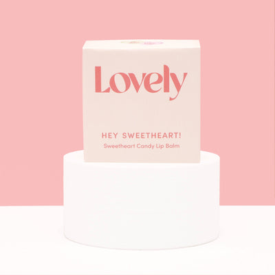 Lip balm packaging with 'Lovely' branding on a pink background