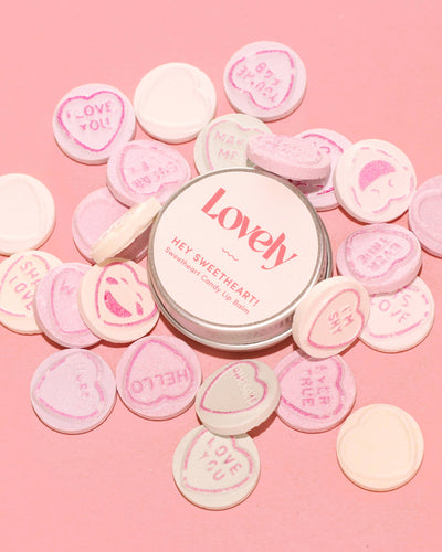 Tin labeled 'Lovely' surrounded by pink and white candy hearts on a pink background