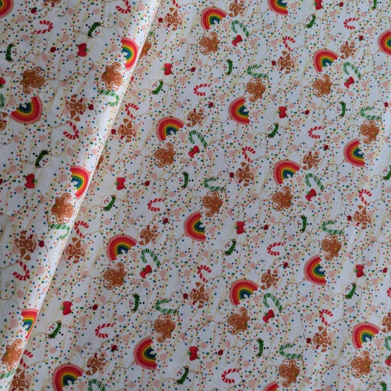Patterned fabric with rainbows, gingerbread men, and candy canes on a white background.