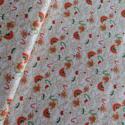 Patterned fabric with rainbows, gingerbread men, and candy canes on a white background.