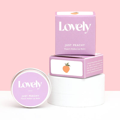 Lovely Just Peachy lip balm with packaging on a pink background
