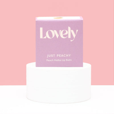 Lip balm packaging with 'Lovely' branding on a pink background