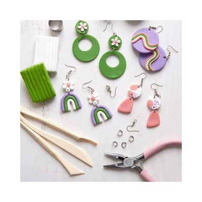 Colorful clay earrings and tools on a white surface
