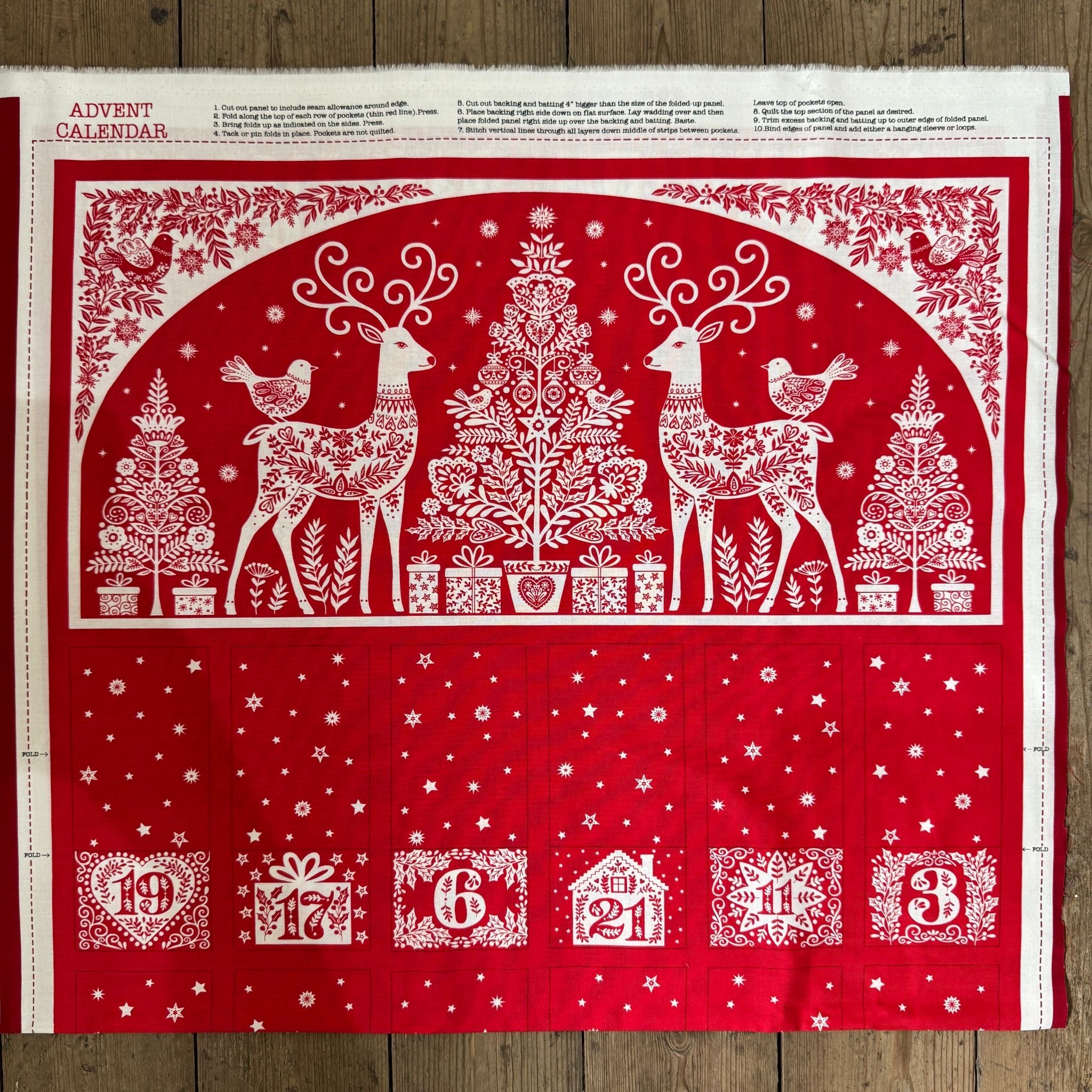 Red and white Christmas-themed advent calendar with reindeer and trees on a wooden surface.