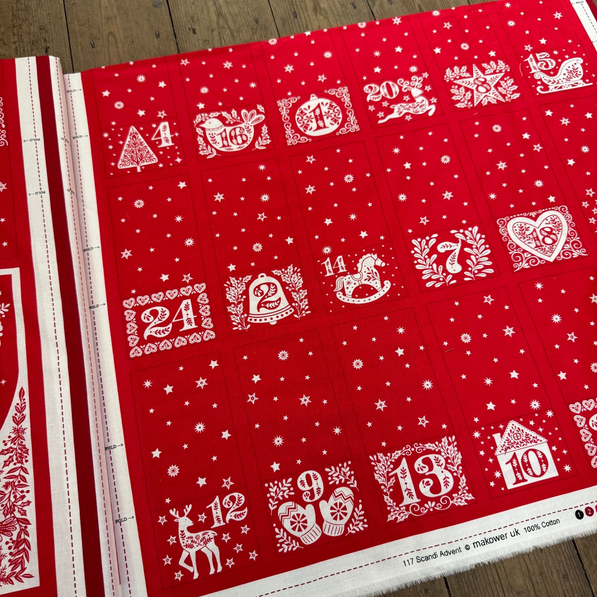 Red and white advent calendar with numbered doors on a wooden surface