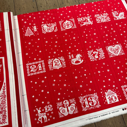 Red and white advent calendar with numbered doors on a wooden surface