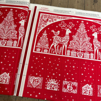 Red and white Christmas-themed fabric with reindeer, trees, and numbers on a wooden surface