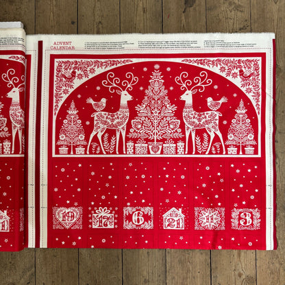 Red and white Advent calendar with reindeer and Christmas tree design on a wooden surface