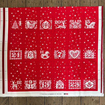Red fabric with white Christmas-themed numbers and designs on a wooden surface