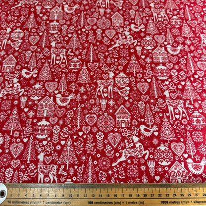 Red fabric with white Christmas-themed patterns including reindeer, trees, and houses.