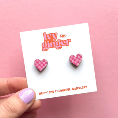 Checkered heart earrings on a 'Ivy and Ginger' branded card against a pink background