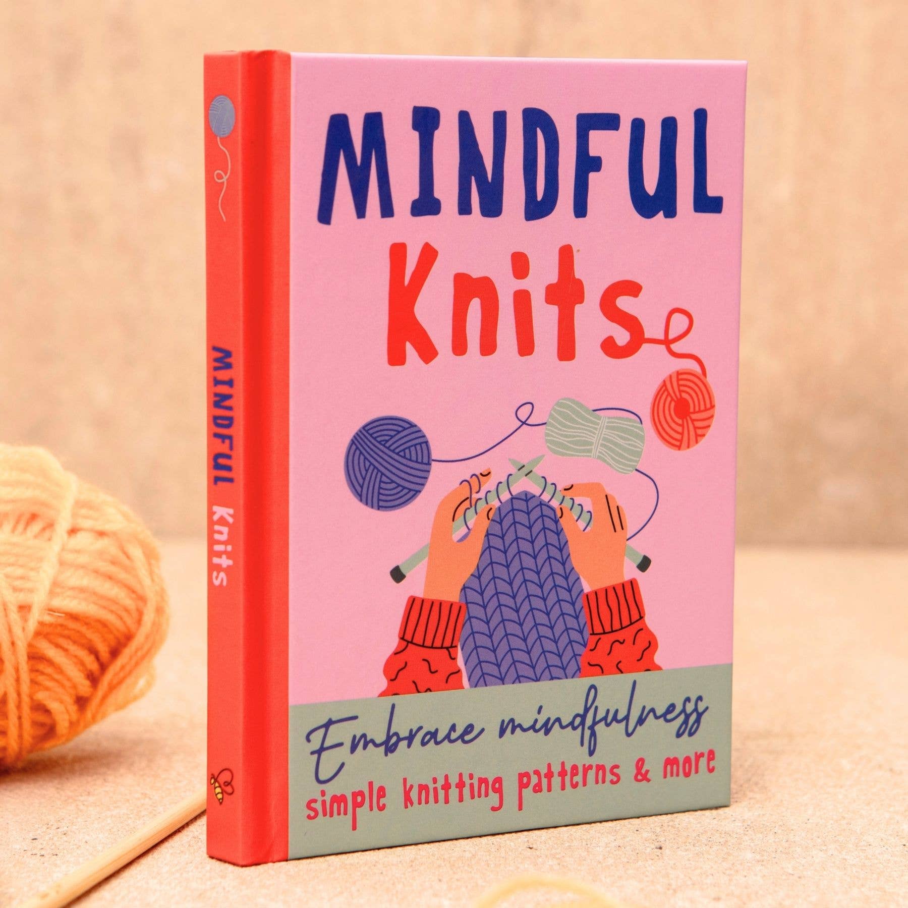 Book titled 'Mindful Knits' with colorful cover design on a wooden surface.