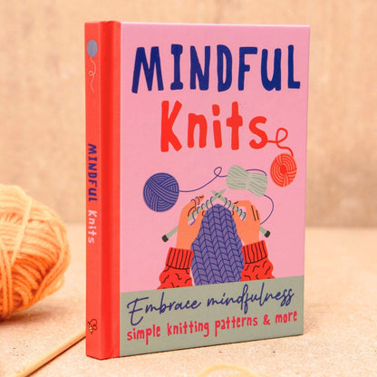 Book titled 'Mindful Knits' with colorful cover design on a wooden surface.