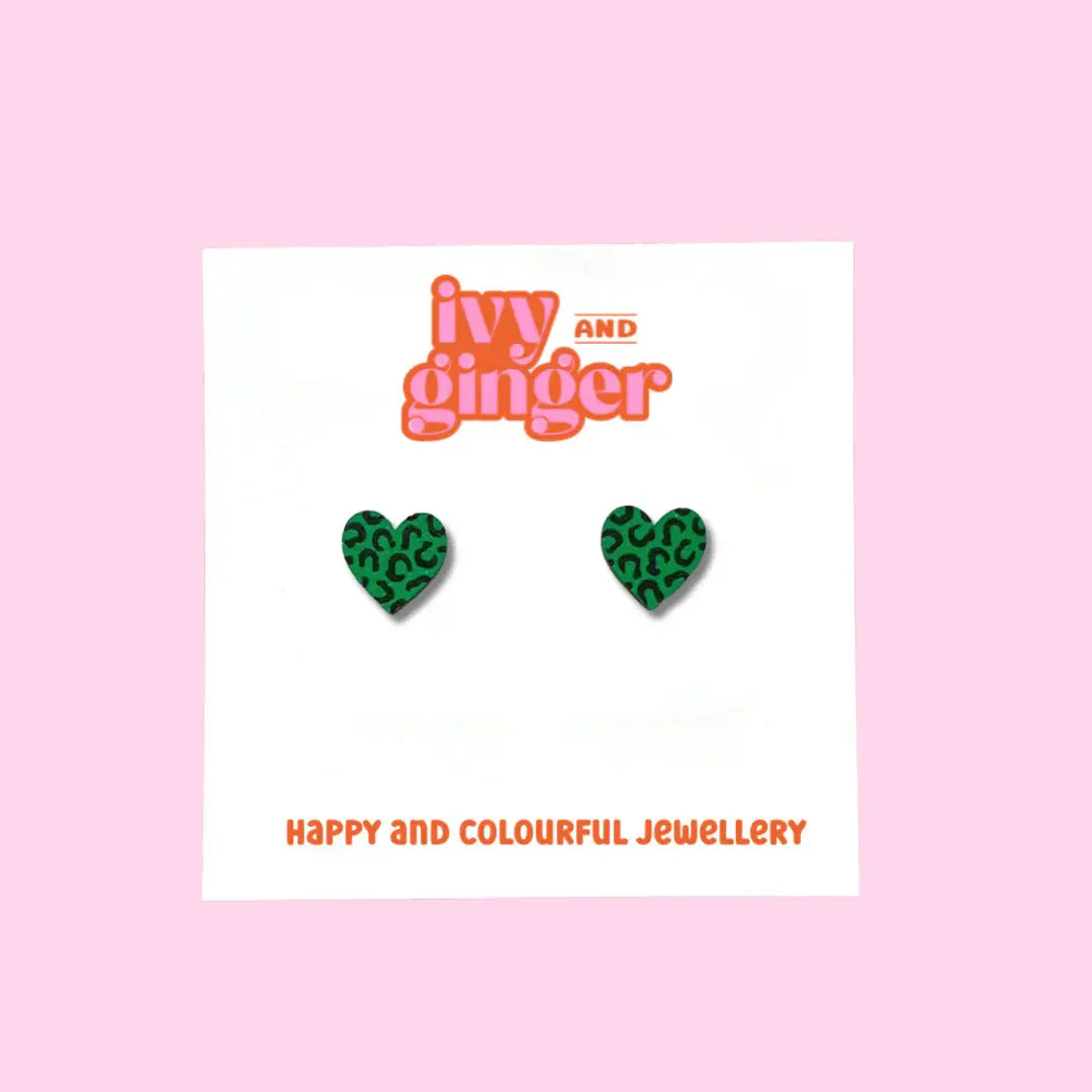 Green heart-shaped earrings on a card with 'ivy and ginger' branding on a pink background