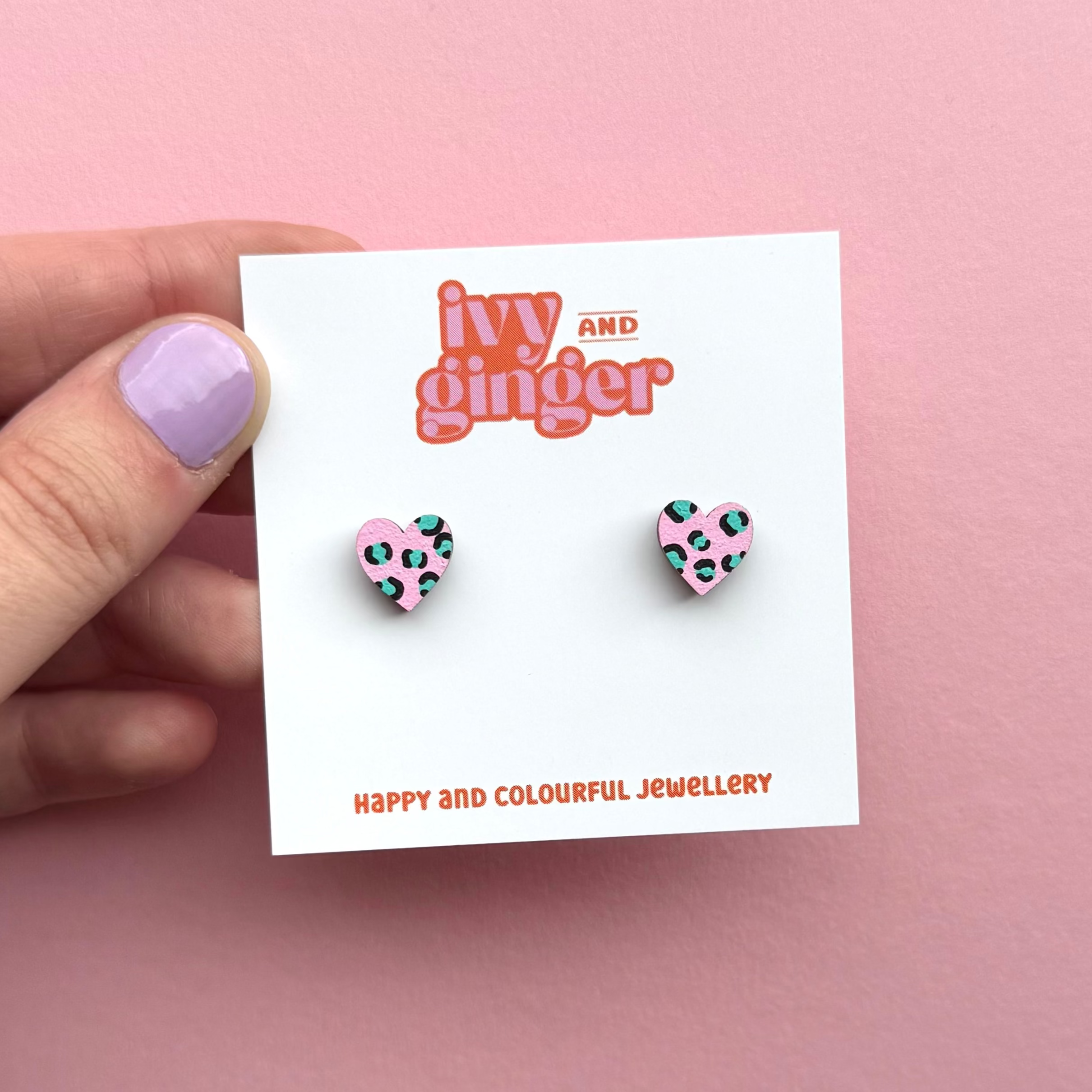 Heart-shaped earrings on a 'Ivy and Ginger' branded card against a pink background