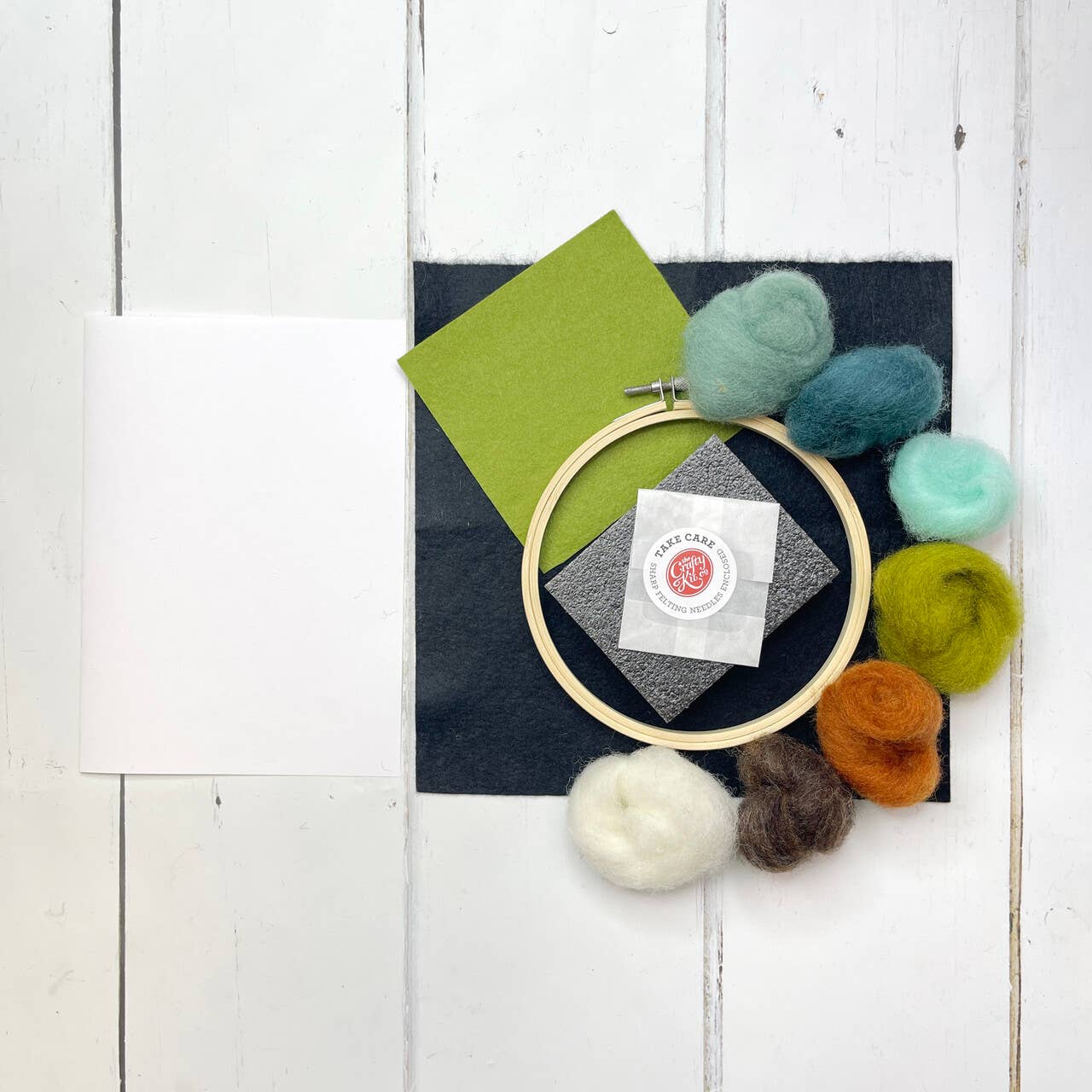 Embroidery hoop with colorful yarn balls on a white wooden surface