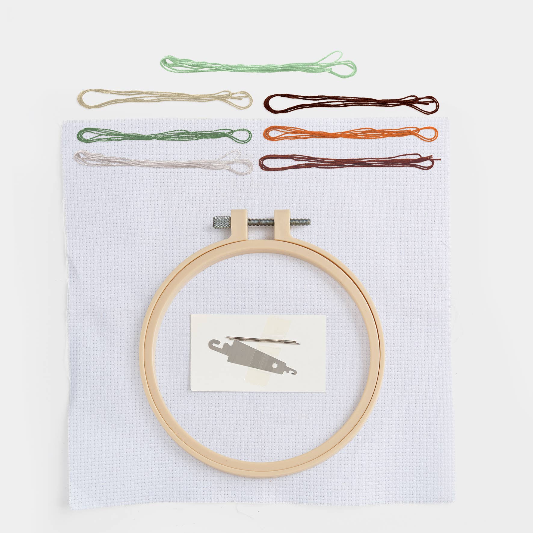 Embroidery hoop with colorful threads and a small card on a white background