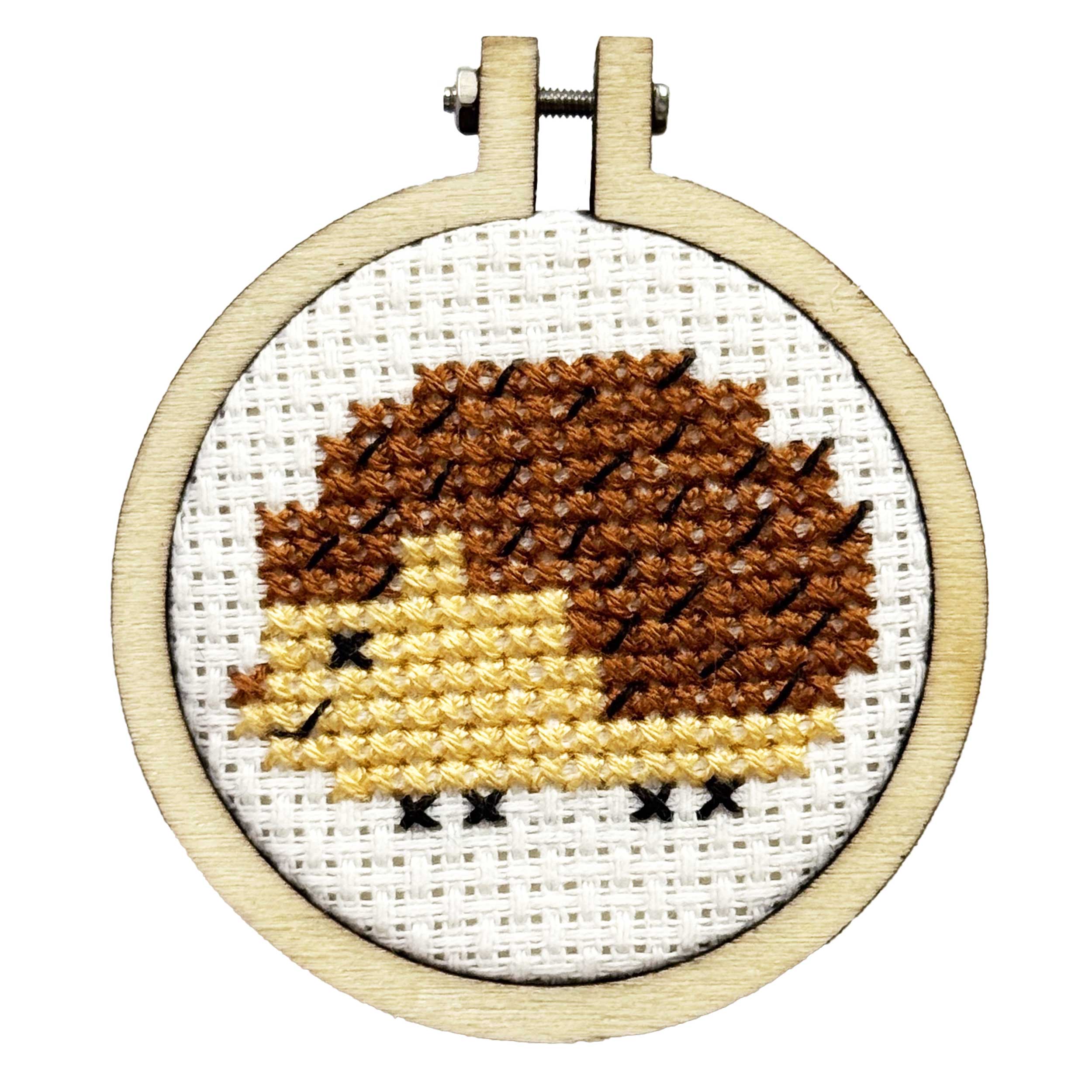 Cross-stitched hedgehog design in a wooden hoop on a white background