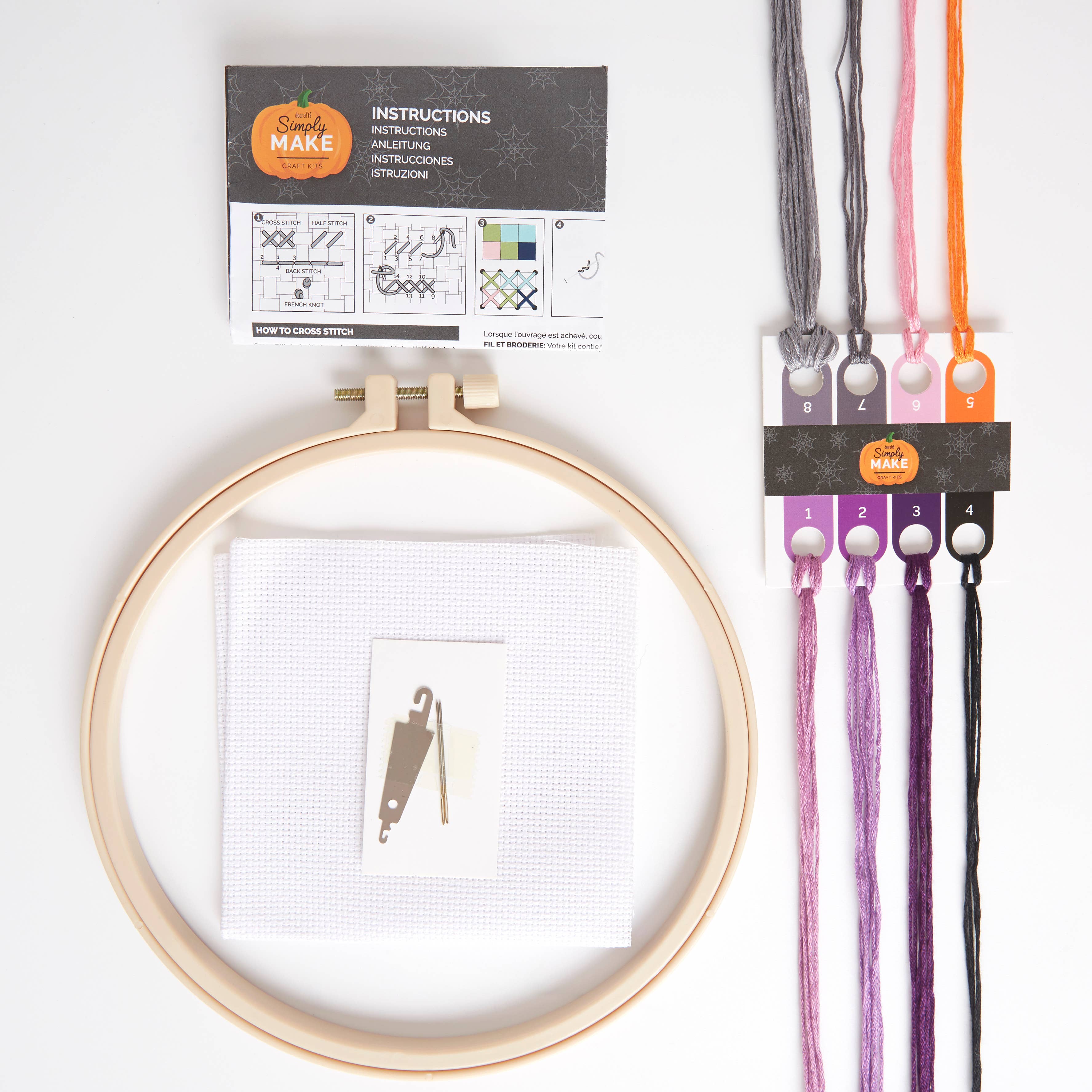 Embroidery hoop with fabric, needles, and thread packages on a white background