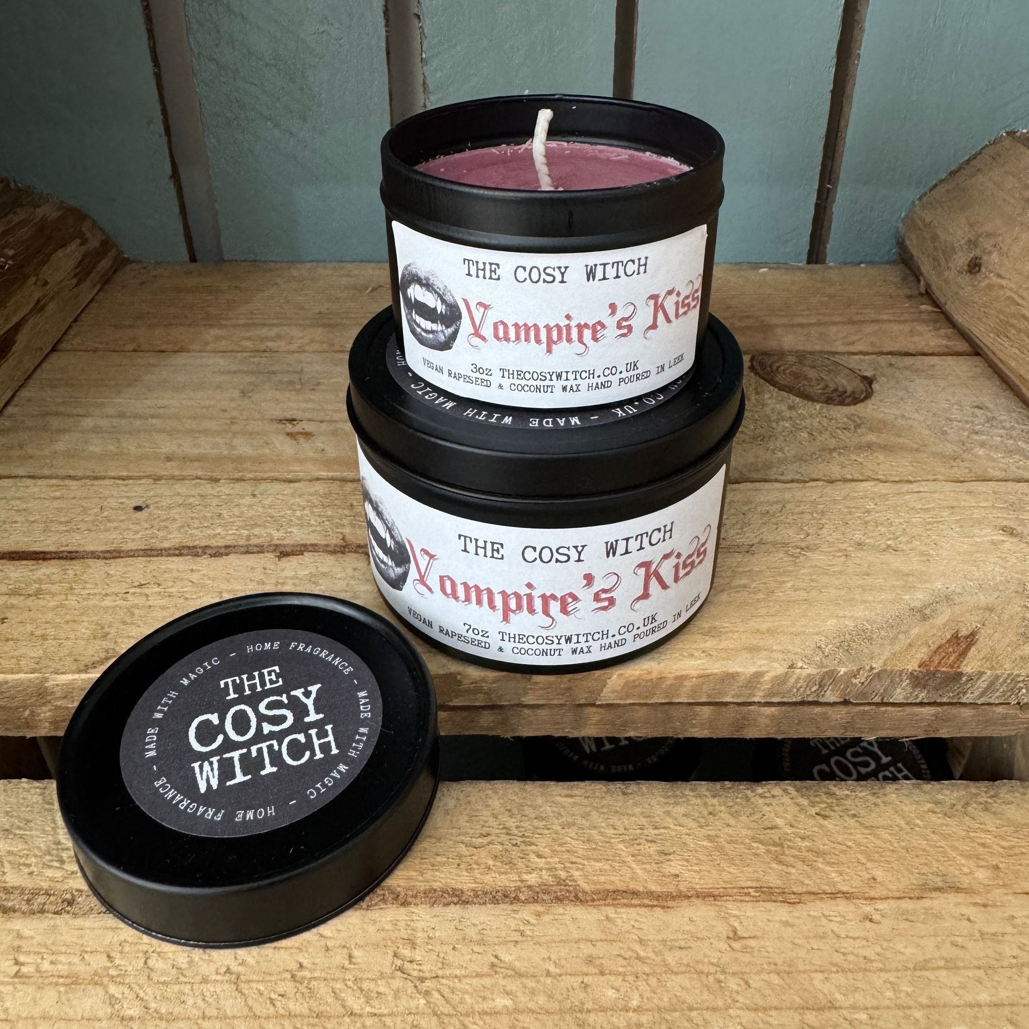 Candle labeled 'Vampire's Kiss' by 'The Cosy Witch' on a wooden surface.