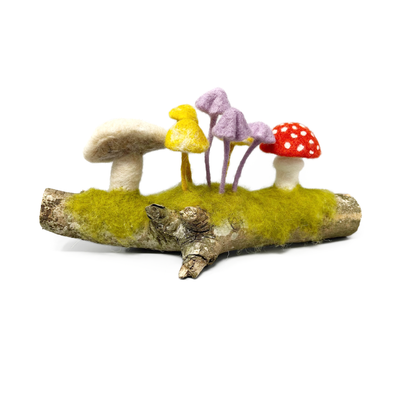 Decorative arrangement of colorful felted mushrooms on a branch with grass.
