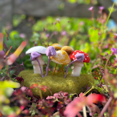 Colorful miniature mushrooms on a green base surrounded by flowers and plants.